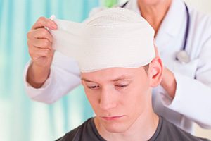 man having head injury wrapped by doctor