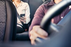 Passenger being driven by an uber driver in the front seat, both wearing seat belts