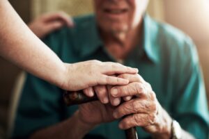 hands of a caring caregiver touching an elder man